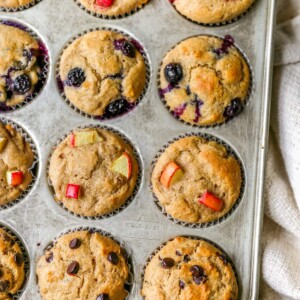 Overhead view of 4 rows of yogurt muffins. Each row contains a different type of yogurt muffin: strawberry, blueberry, apple and chocolate chip.