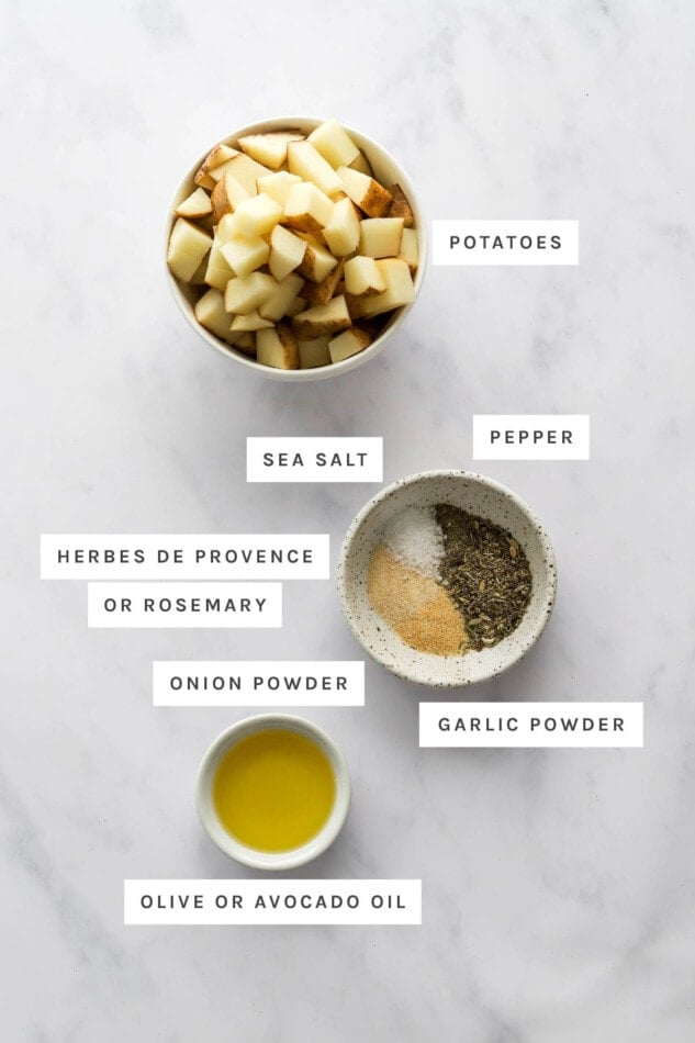 Ingredients measured out to make air fryer breakfast potatoes: potatoes, sea salt, pepper, herbes de provence/rosemary, onion powder, garlic powder and olive/avocado oil.