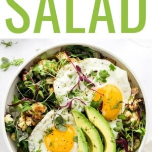 Salad topped with sunny-side-up eggs and avocado.