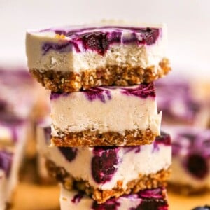Stack of four blueberry cheesecake bars. The top one has a bite taken from it.