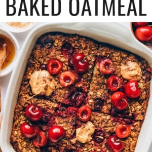 Baking dish of cherry baked oatmeal topped with cherries and nut butter.
