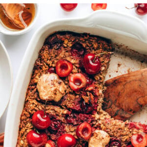 Baking dish with cherry baked oatmeal. One slice is cut out of the baked oatmeal.