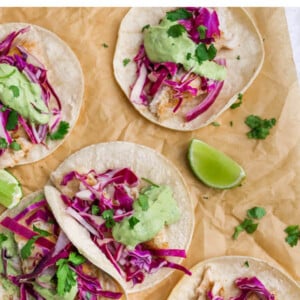 Fish tacos topped with slaw and avocado crema.