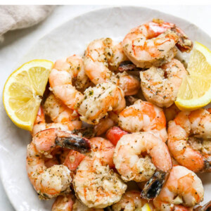 Plate of grilled shrimp garnished with lemon slices.