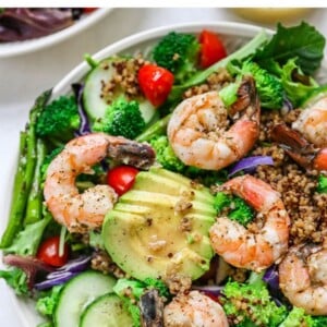 Salad topped with grilled shrimp, quinoa, tomatoes, avocado, cucumber and cabbage.