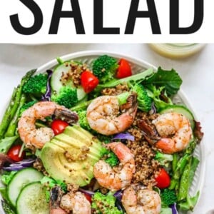 Salad topped with grilled shrimp, quinoa, tomatoes, avocado, cucumber and cabbage.