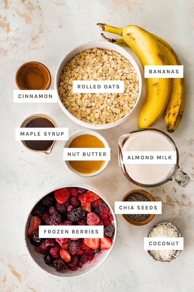 Ingredients measured out to make one pan baked oatmeal: oats, bananas, cinnamon, maple syrup, nut butter, almond milk, chia seeds, frozen berries and coconut.