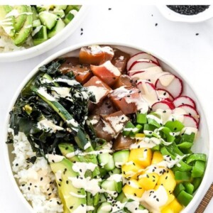 Homemade tuna poke bowl topped with black sesame seeds and sriracha mayo.