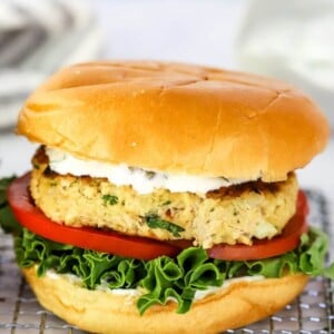 Salmon burger on a bun with lettuce, tomato and herb sauce.