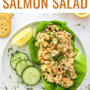 Salmon salad plated over a bed of lettuce and cucumber and lemon slices on the side.