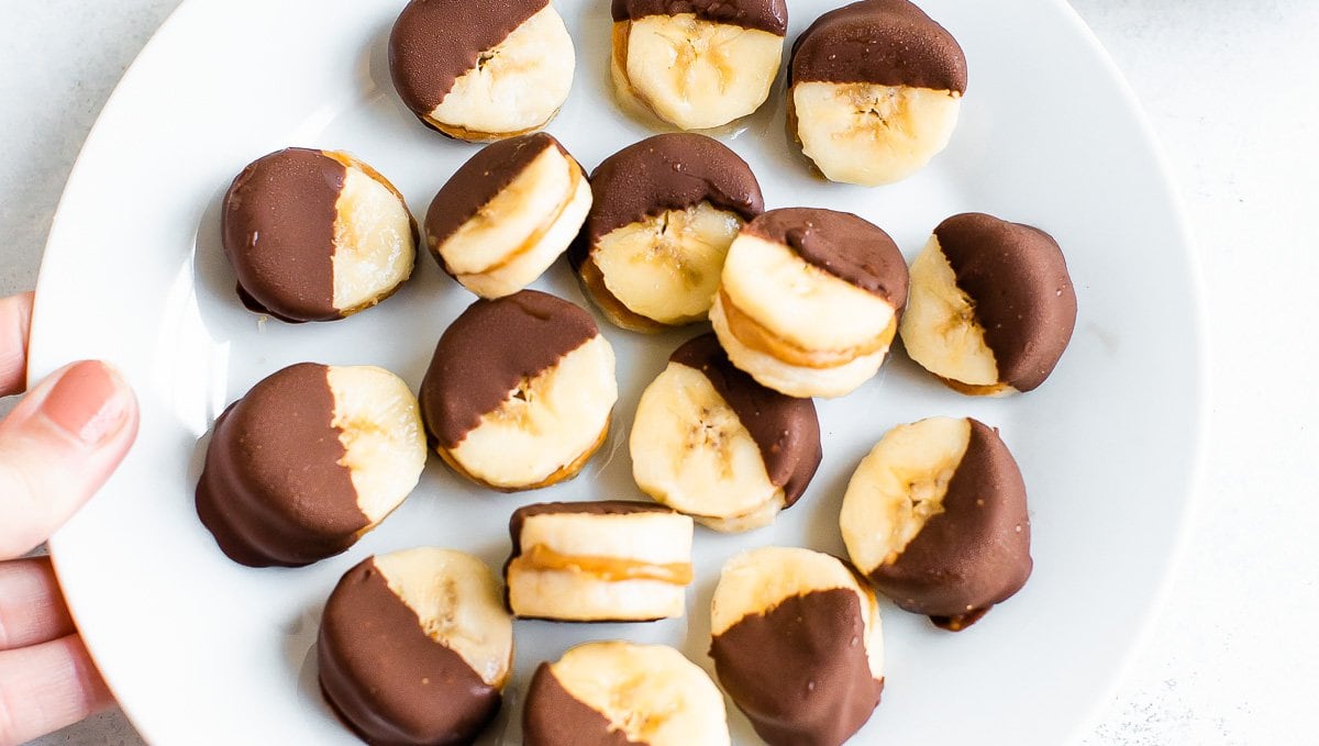Peanut butter filled banana bites dipped in chocolate on a plate.