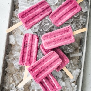 A tray of ice with greek yogurt popsicles laying on top.