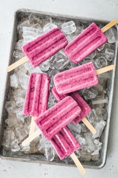 A tray of ice with greek yogurt popsicles laying on top.