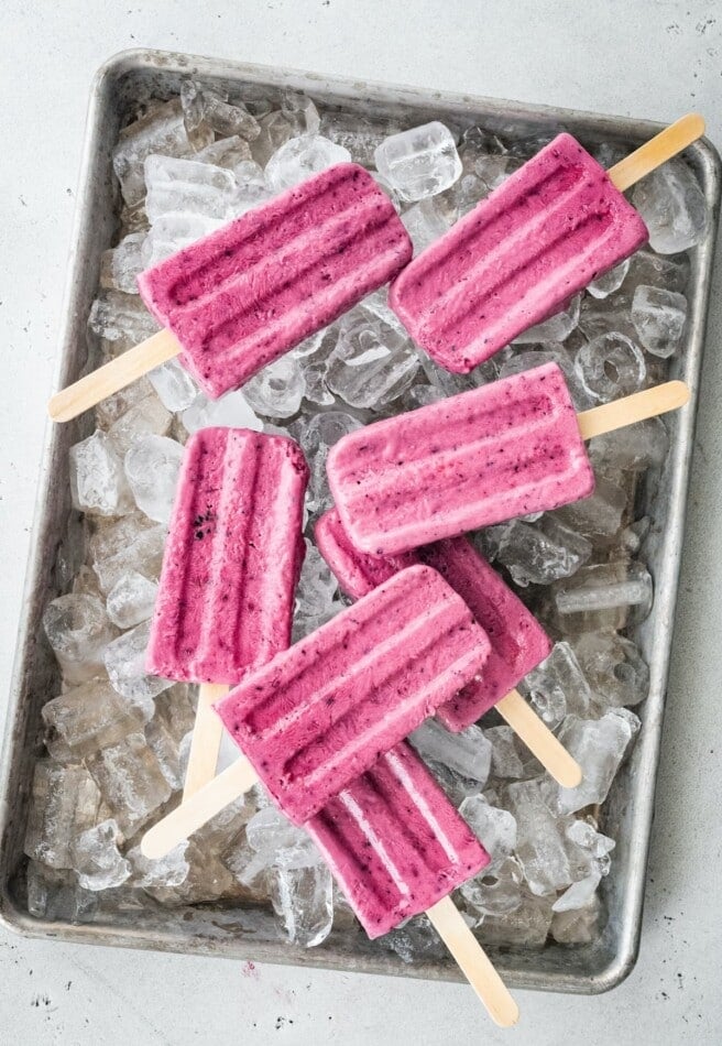 A tray of ice with greek yogurt popsicles laying on top.
