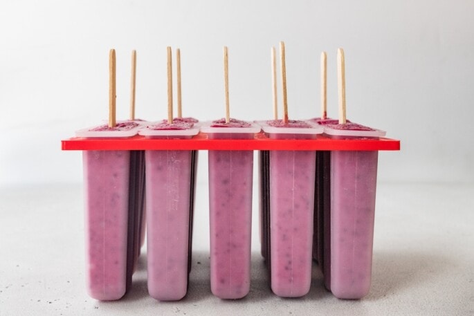 Head on view of an 10-popsicle mold with sticks sticking out of the top.