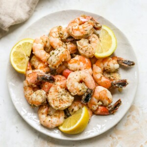 Overhead plate of grilled shrimp on a plate with lemon wedges.