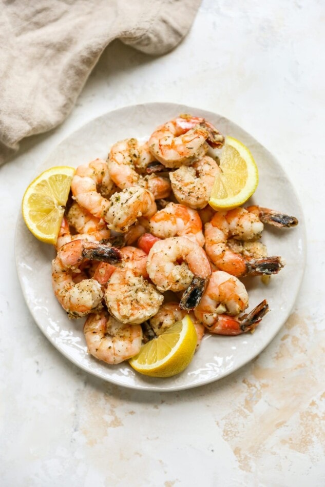 Overhead plate of grilled shrimp on a plate with lemon wedges.