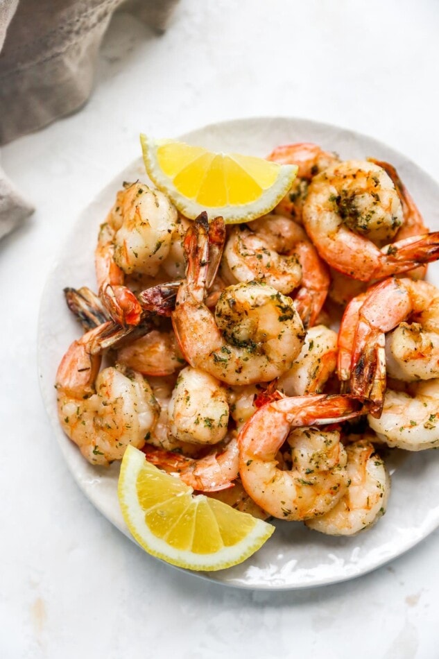 Grilled shrimp on a plate with lemon wedges.