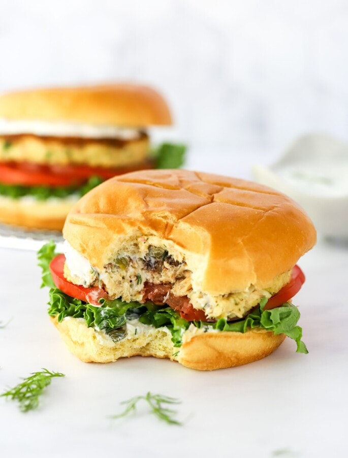 A salmon burger with a bite taken out of it.