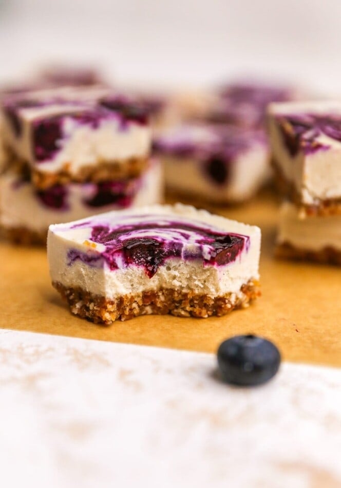 A vegan blueberry cheesecake square with a bite taken out of it.
