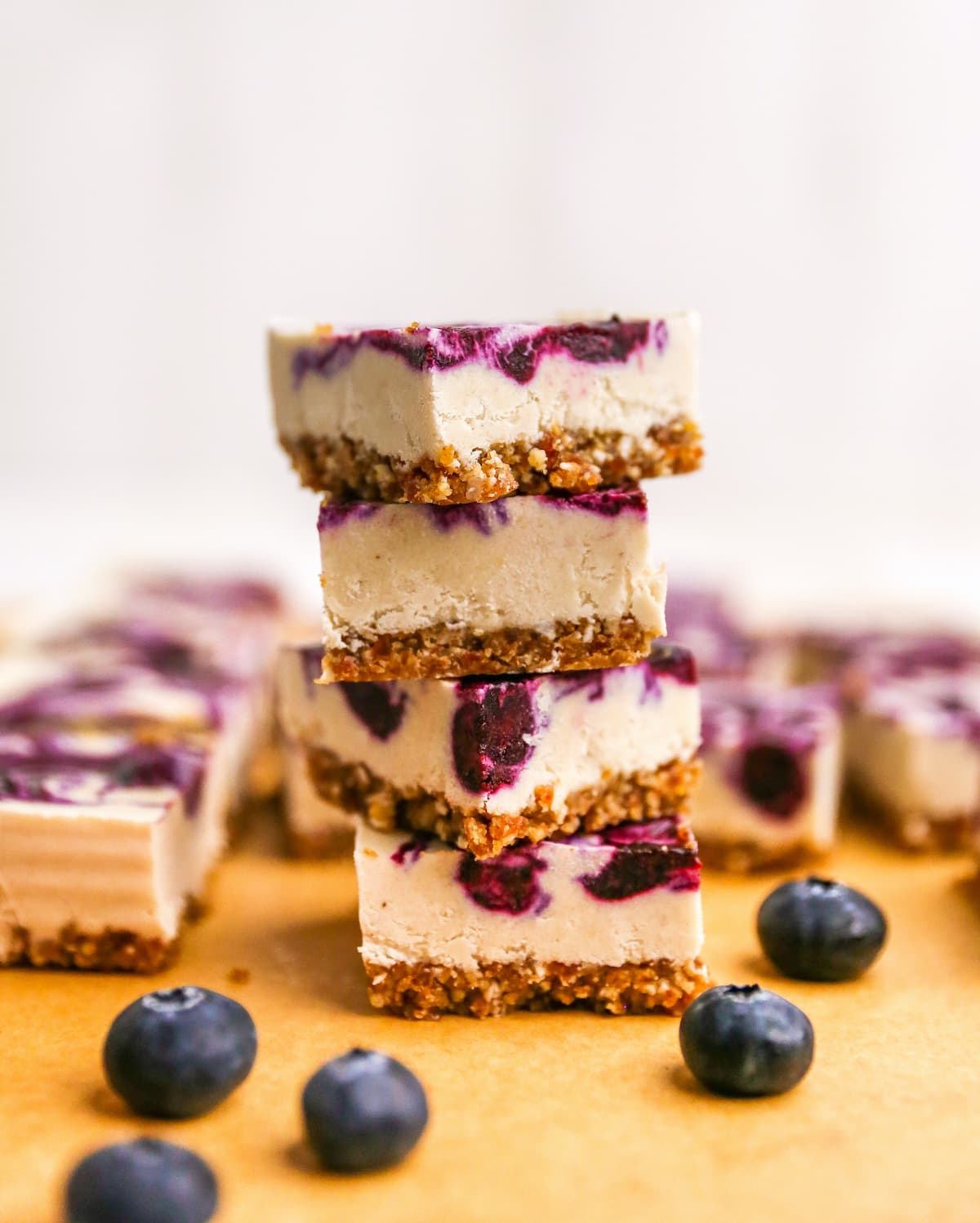 Four vegan blueberry cheesecake bars stacked on top of each other.