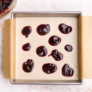 Dollops of blueberry sauce added to square baking pan.