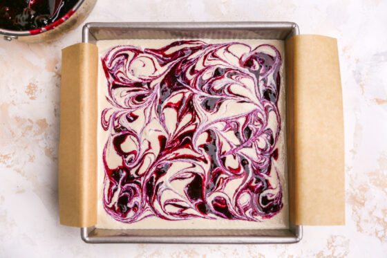 Blueberry dollops swirled with the vegan "cheesecake" filling in a square baking pan.
