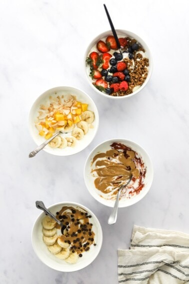Overhead view of 4 different varieties of yogurt bowls.