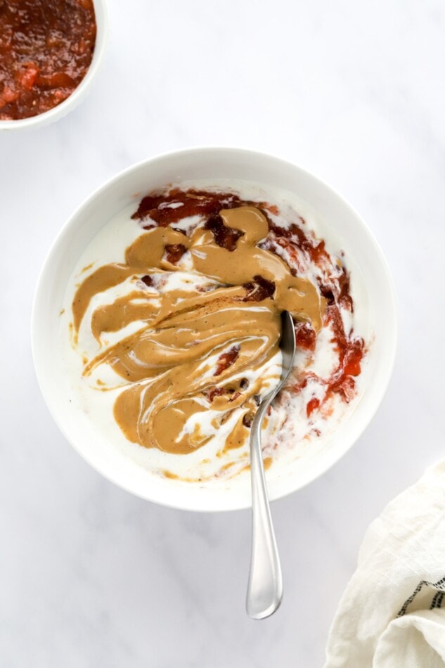Peanut butter and jelly swirled yogurt bowl with a spoon.