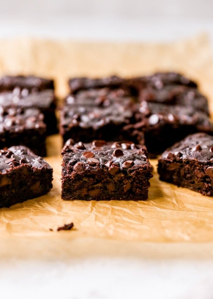 Zucchini brownie squares on a sheet of parchment paper.
