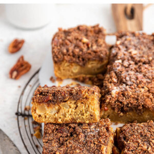 Slices of apple cake stacked on a cutting board lined with parchment paper.