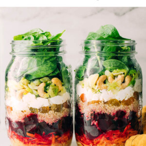 Two mason jars layered with ingredients to make beet power salads for meal prep.
