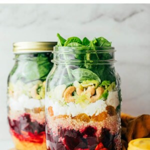 Two mason jars layered with ingredients to make beet power salads for meal prep.