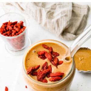 Glass full of a Butterfinger smoothie, topped with goji berries.