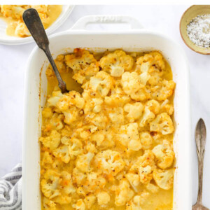 Overhead view of baked cauliflower mac and cheese in a baking dish. Some servings have been removed.