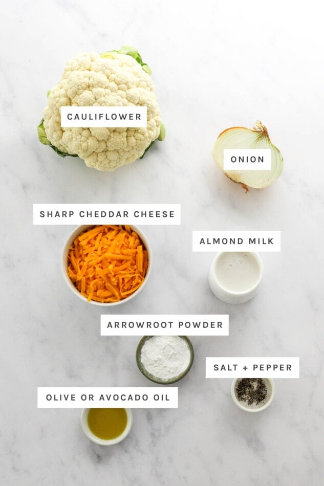 Ingredients measured out to make Baked Cauliflower Mac and Cheese: cauliflower, onion, sharp cheddar cheese, almond milk, arrowroot powder, salt, pepper and oil.