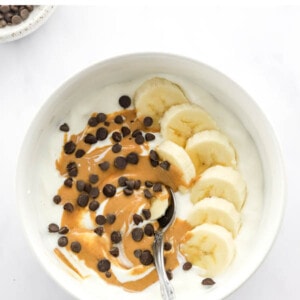 Yogurt bowl topped with banana, chocolate chips and peanut butter.