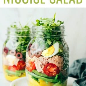 A mason jar layered with ingredients to make a nicoise tuna salad.