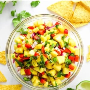 Pineapple salsa in a serving bowl with chips scattered around.