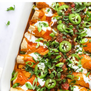 Baked vegan enchiladas topped with green onion and jalapeño slices.