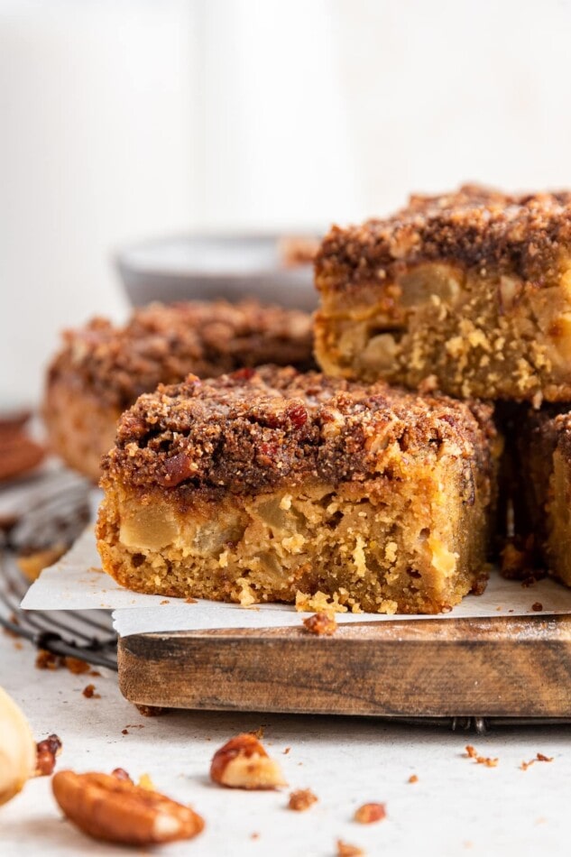 Slices of apple cake stacked on a cutting board lined with parchment paper.