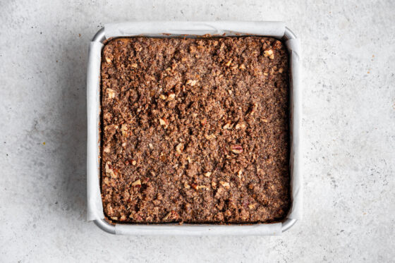 Baked apple cake in a square baking pan lined with parchment paper.