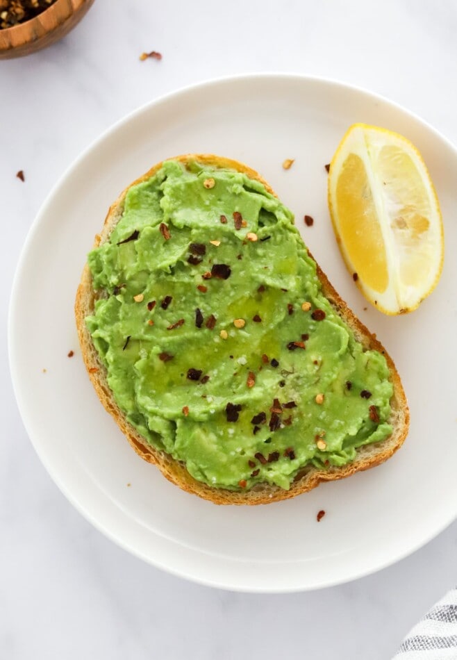 Basic avocado toast served on a plate with a lemon wedge.