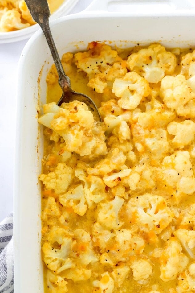 Overhead view of baked cauliflower mac and cheese being served with a spoon.