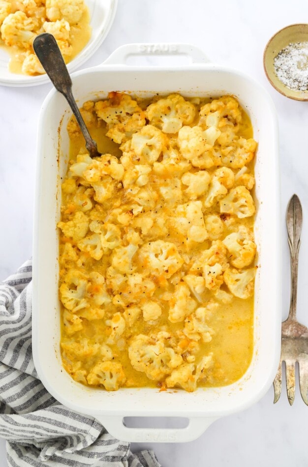 Overhead view of baked cauliflower mac and cheese in a baking dish. Some servings have been removed.
