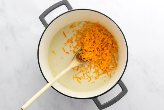 Cheese added to sauce cooking in pot.