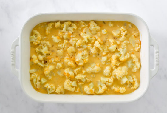 Cauliflower and cheese sauce spread in baking dish.