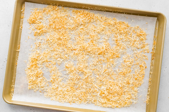 Toasted coconut flakes spread across a sheet pan lined with parchment paper.