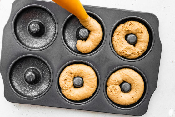 Piping donut batter into donut pan.