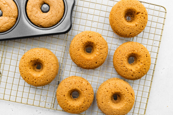 Freshly baked donuts cooling on wire rack.